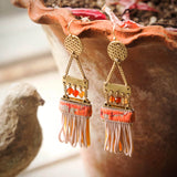 ladder earrings with tassels are hanging off the edge of a terracotta pot