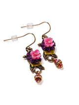 close up of drop earrings with green velvet, purple applique, and pink resin flowers