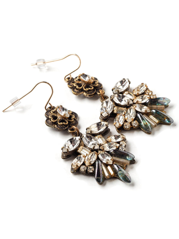 Three quarter closeup view of a pair of ornate statement earrings with rhinestone navettes and floral tops