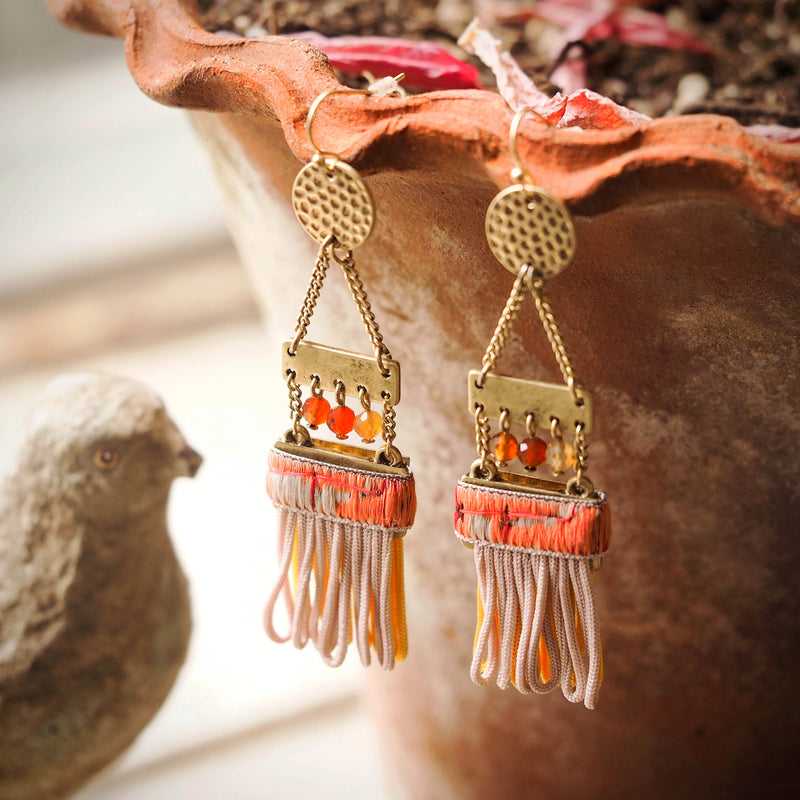 ladder earrings with tassels are hanging off the edge of a terracotta pot